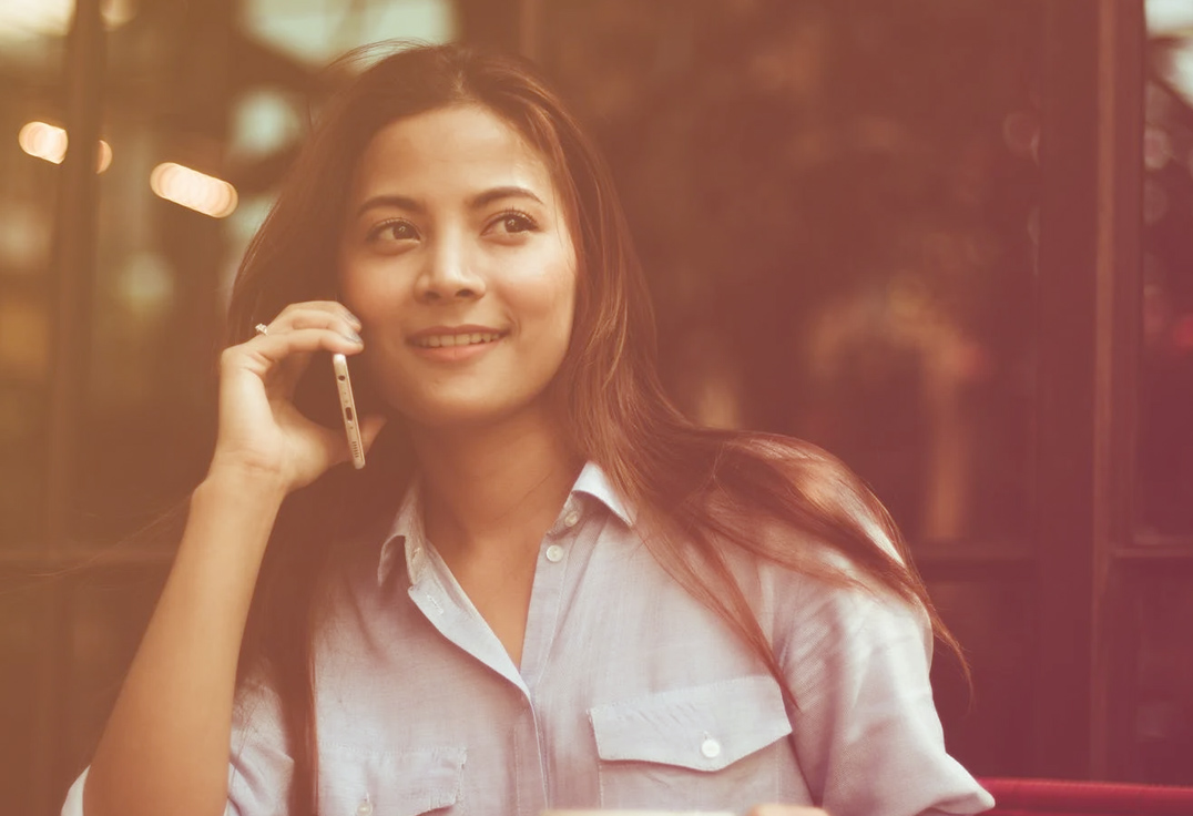 Femme souriante au téléphone, contactez-nous par mail ou par téléphone